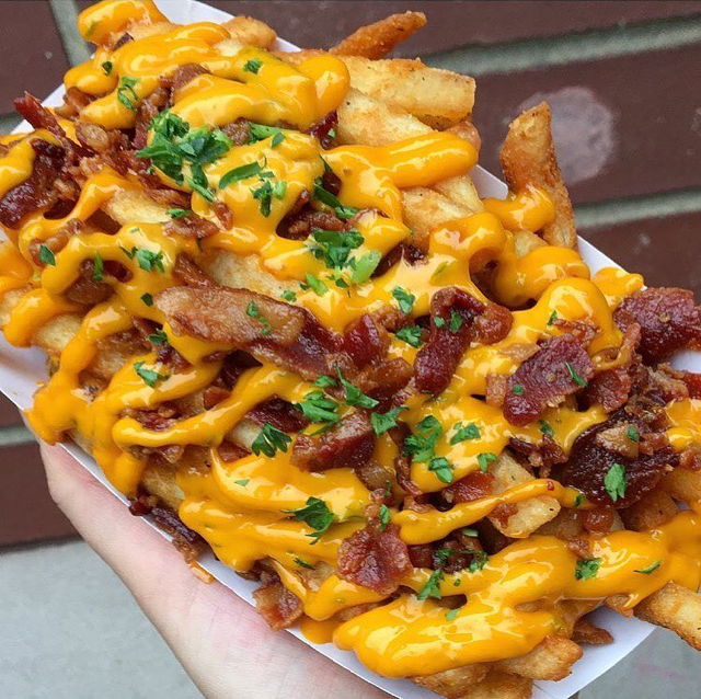 Salchipapa con tocino y queso. Comida rápida latinoamericana.