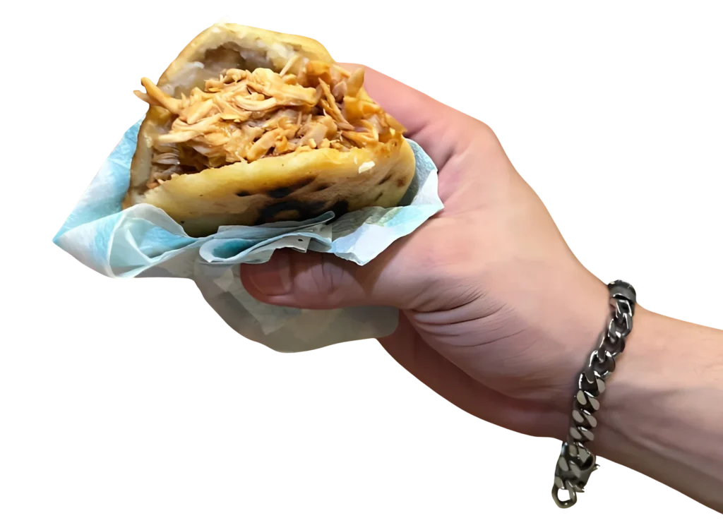 Inicio 2 Mano con una Arepa Naguara, rellena de pollo. Comida con sazón.