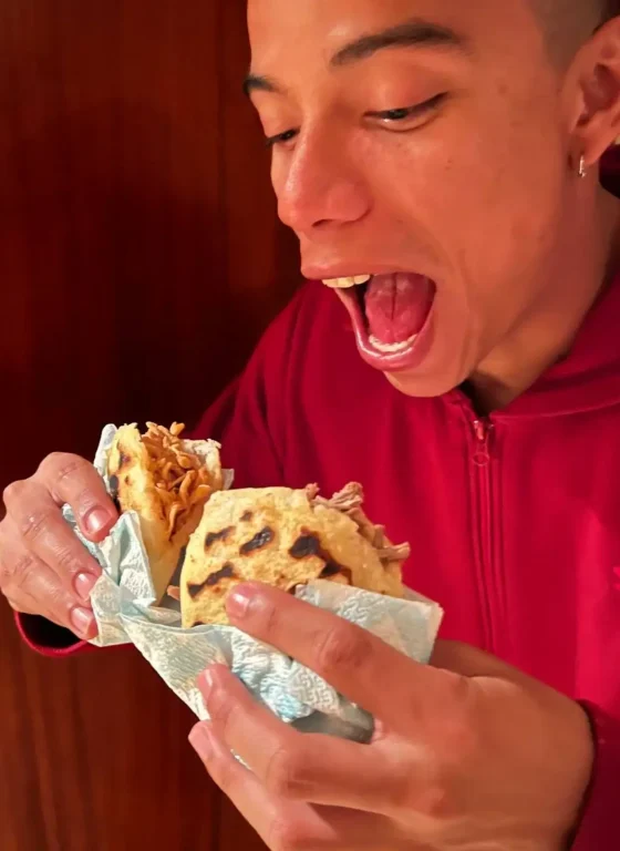 Chico colombiano comiendo dos arepas en España, Tarragona, una de carne y otra de pollo.