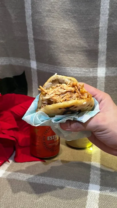 Mà amb una Arepa Naguara, farcida de pollastre. Al costat d'una flor de Nadal.